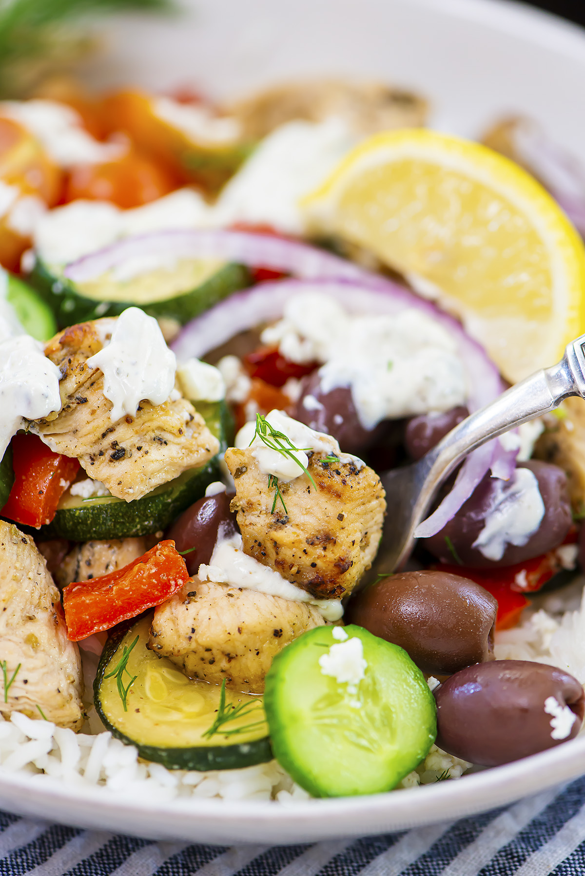 A fork dipping into a bowl of Greek chicken rice.