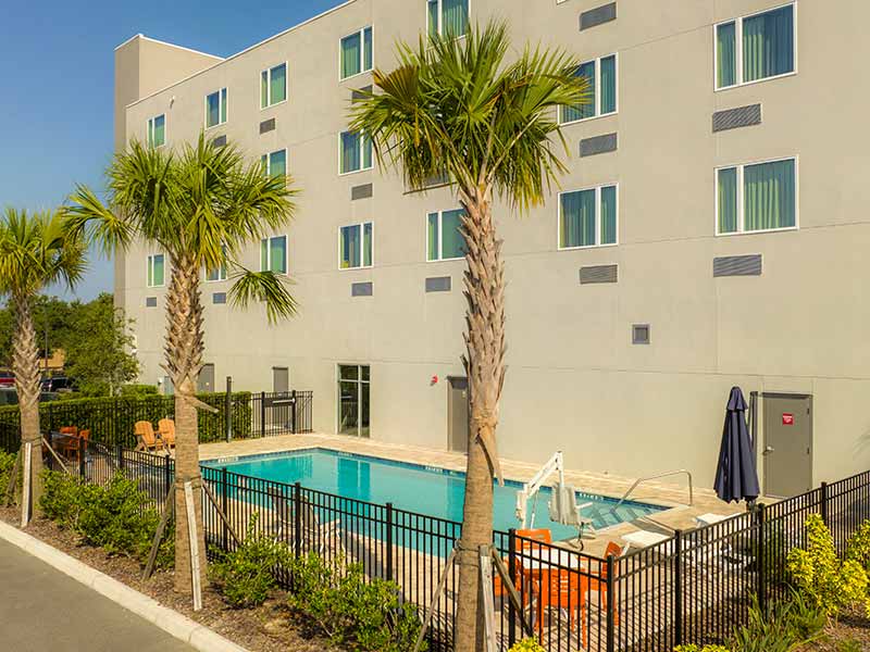 Hotel swimming pool in Orlando with trees and building next door