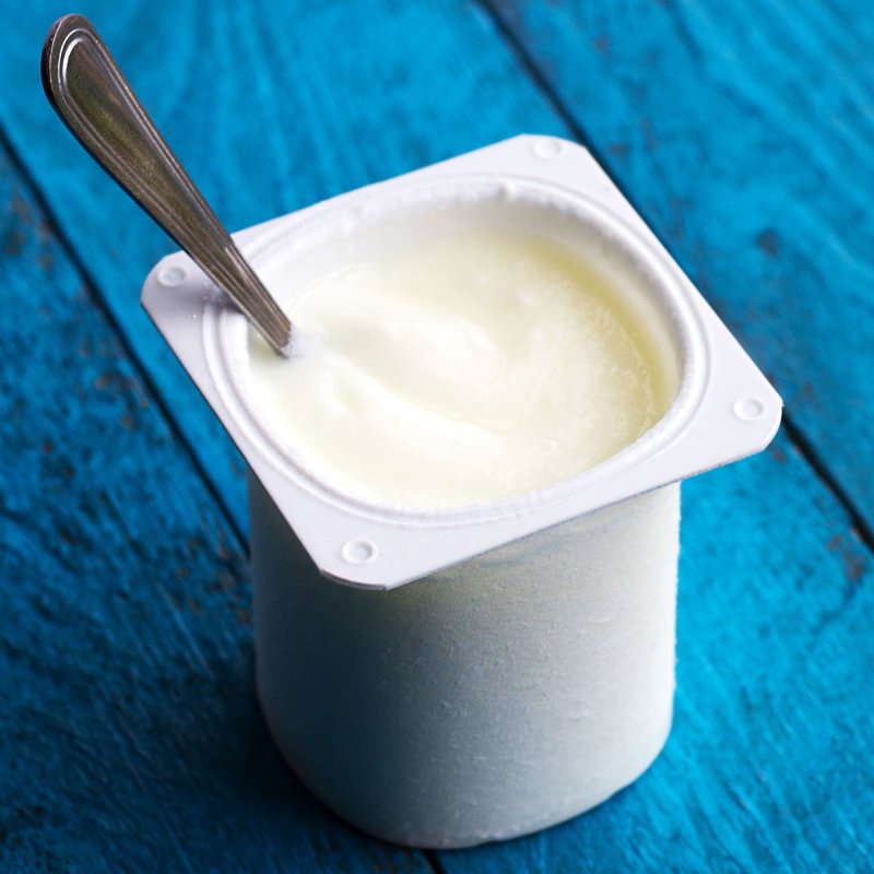 Traditional yogurt pot with a spoon inside on a table.