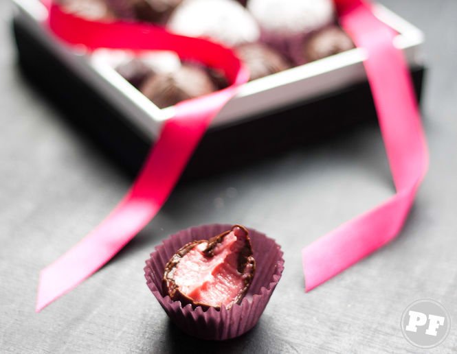 Bitten Champagne truffle showing whole on dark table with box of truffles behind