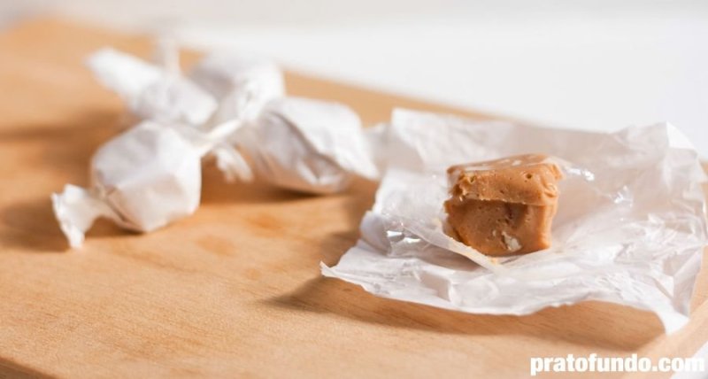 Caramelized White Chocolate Fudge sliced ​​unwrapped from parchment paper on wooden cutting board