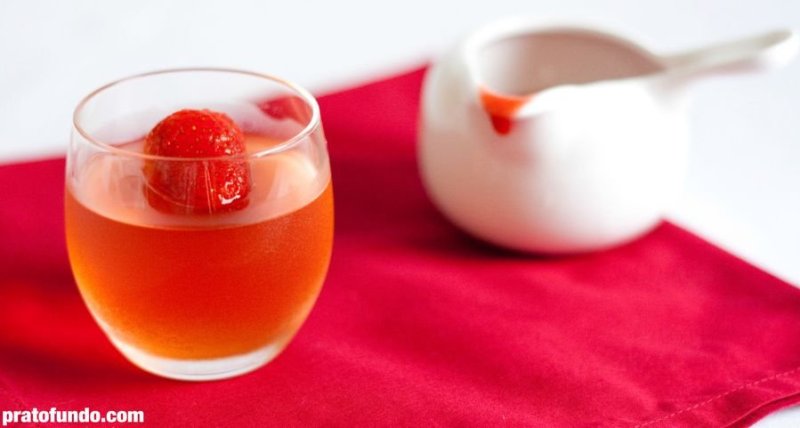 Champagne jelly with strawberry on top and white pot with strawberry syrup in the background