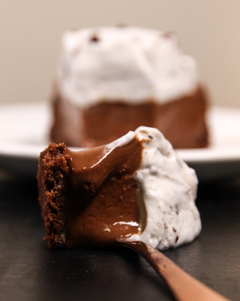 Chocolate mousse pie on a spoon seen from the front on a table.