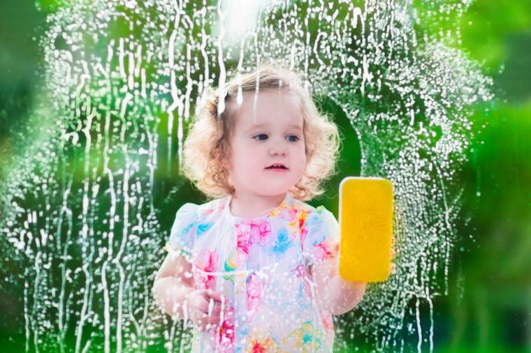 Girl cleaning the window with a sponge