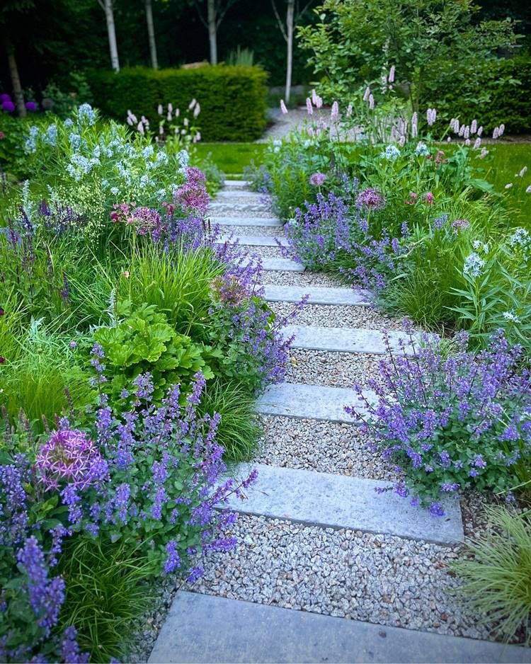 Caminho de jardim com pedras e plantas como lavanda.