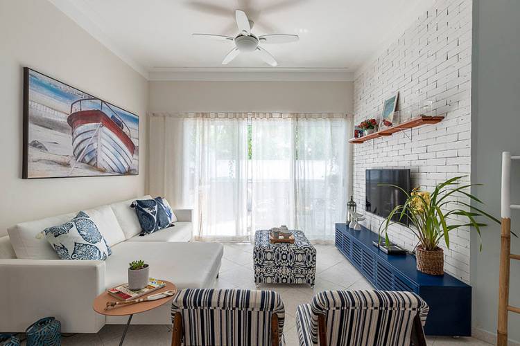 Living room with blue rack, armchairs, white sofa, boat painting and large window. 