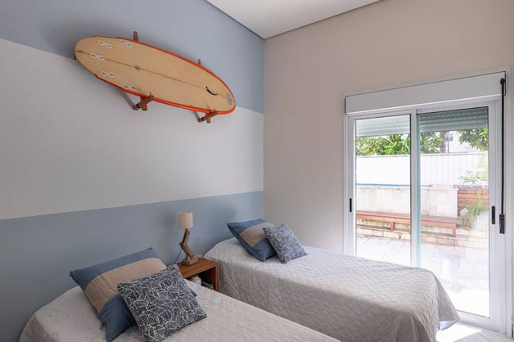 Bedroom with two single beds, blue and white wall and surfboard. 