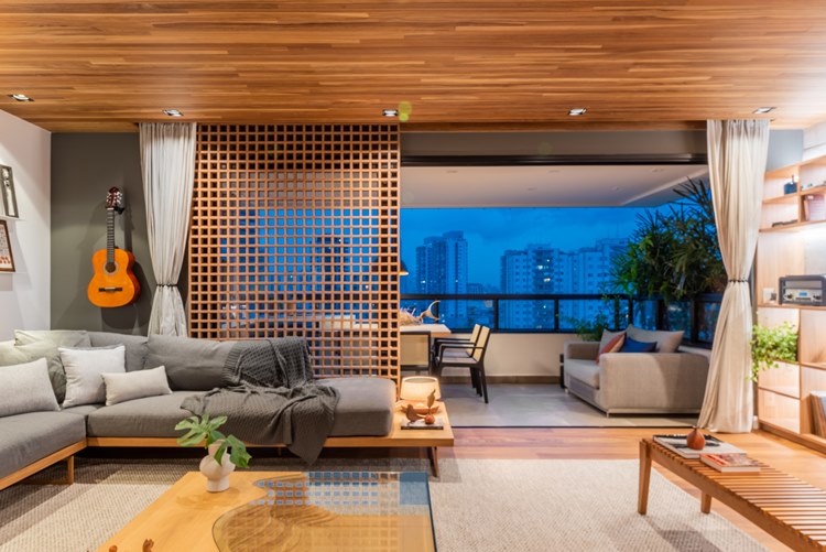 Living room of the decorated 187 m² apartment.  Gray sofa and armchairs with cushions, integrated with the house's balcony, with a table and another sofa that overlooks the city