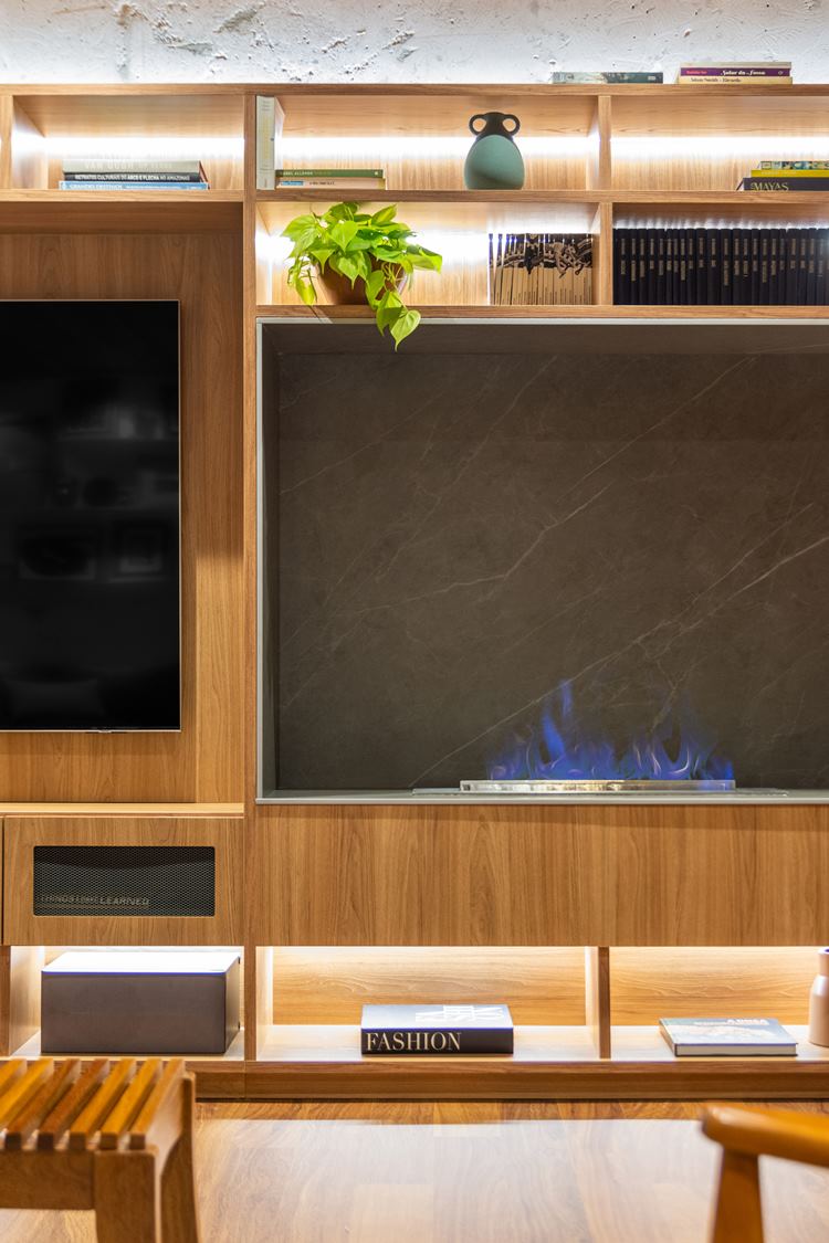 Fireplace in the home theater of the decorated 187 m² apartment.  Porcelain tile finish that imitates gray marble.  Boa constrictor plants, books, boxes and other objects decorate the furniture’s sections