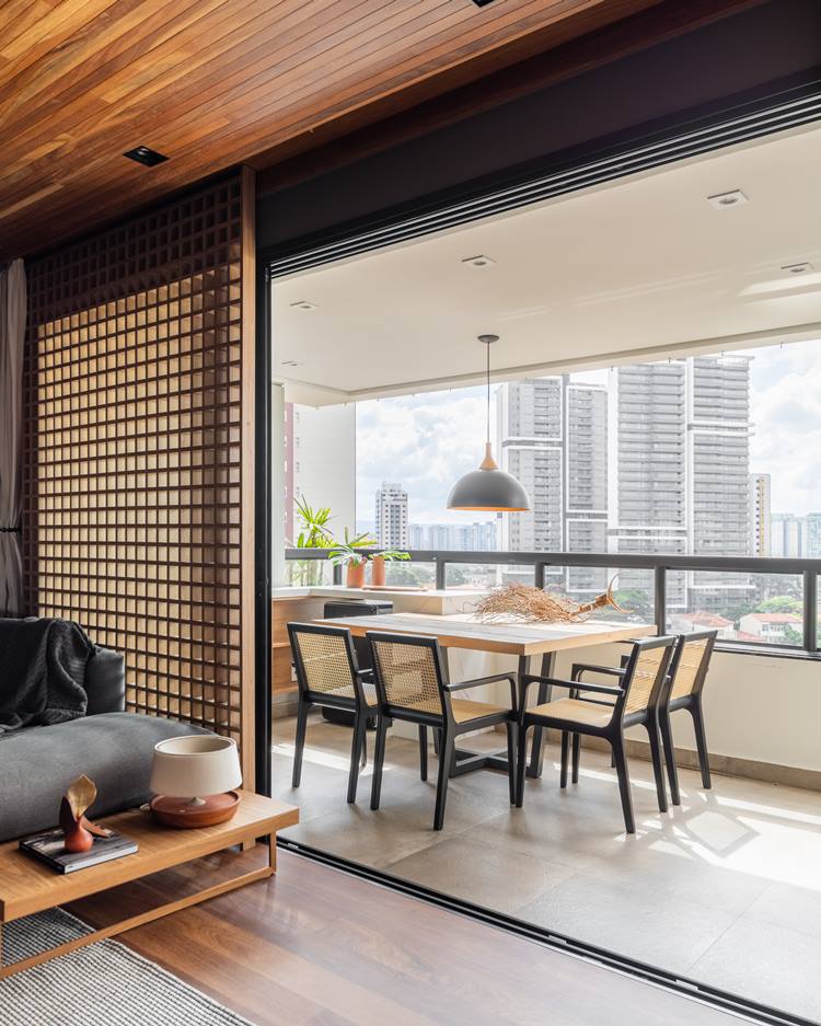 Balcony of the decorated 187 m² apartment.  Table with 4 chairs, with black and bronze lamp.  Decorating in the center, a dry rooted trunk. 