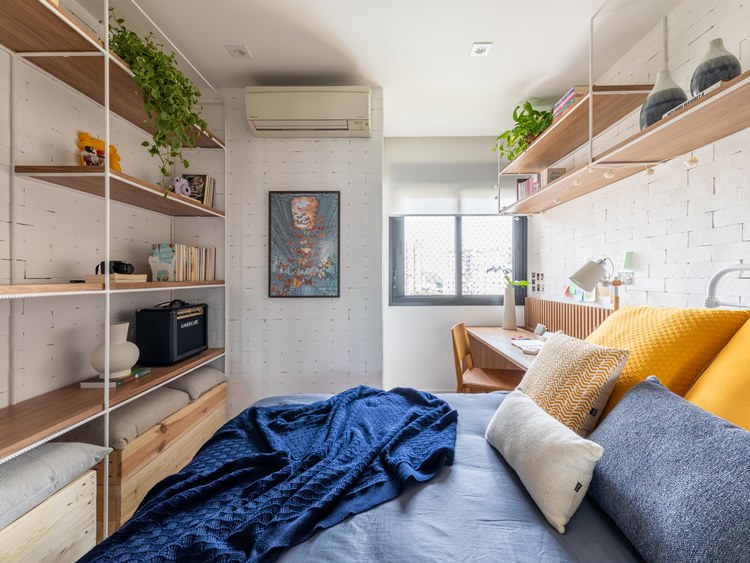 older sister's room in the decorated 187 m² apartment.  neutral colors, dark blue, gray and yellow layette.  Photo towards the window, which has a study table next to it.  In front of the bed, a shelf with various items, such as books and plants.