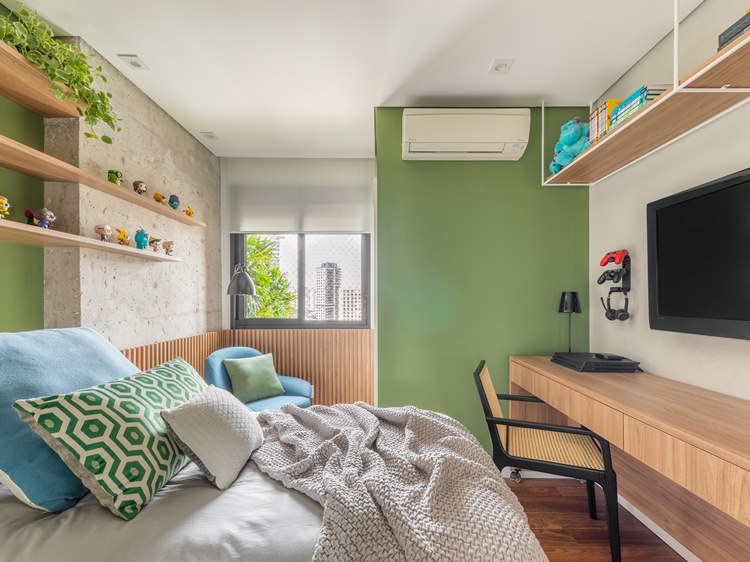 Youngest son's room, green colors and neutral tones, bed with green, blue and gray linen.  Blue armchair with green cushion.  The bed has a wall in front with a television, video game, chair with table and a shelf with objects above.  Above the headboard of the bed, shelves with plants and animals decorating