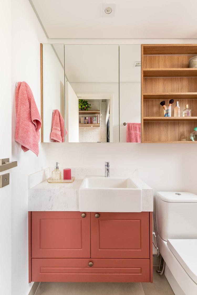 Bathroom in sister's room, with pink sink, toilet and hanging cabinet with mirror and shelves with beauty items