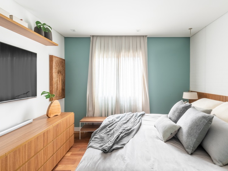 Double bedroom with king size bed.  In front, furniture with drawers, TV on the wall and shelf on top with vases, Adam's rib leaf and more boxes.  On the wall, a painting decorates.