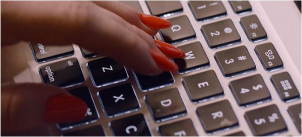 Woman wearing nail polish and typing on computer