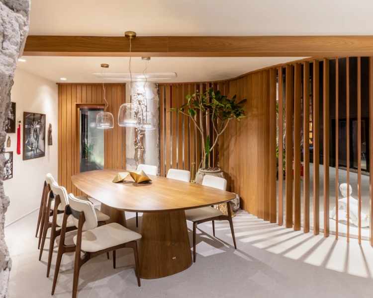 Dining room with table and wooden details.  In the corner there is a pot with a small tree.