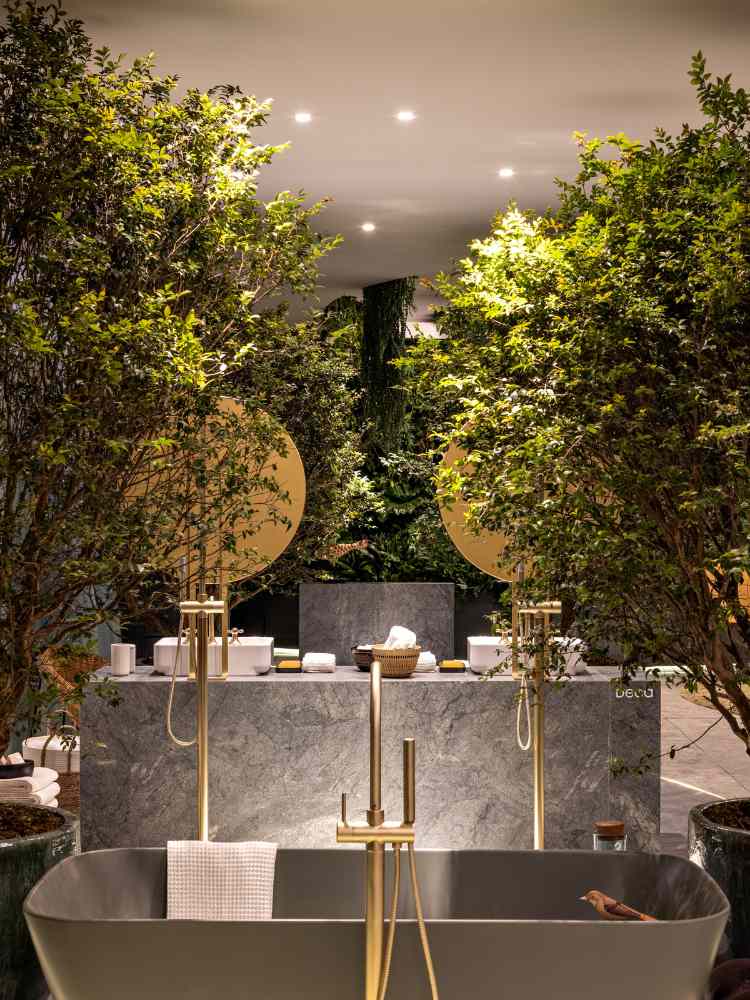 gray bathtub with golden tap and two trees, one on each side