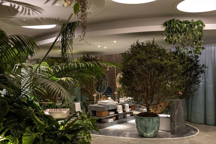 Bathroom with gray and gold tones filled with large plants.