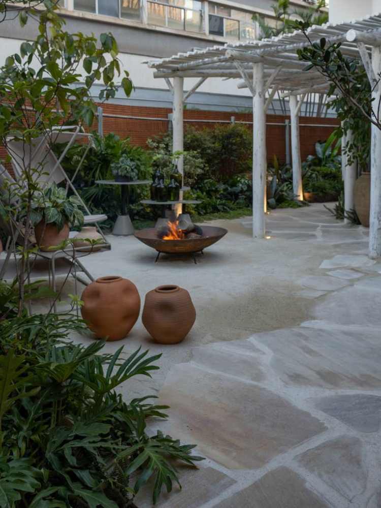 outdoor area with plants, vases, a chair and a fireplace in the center.