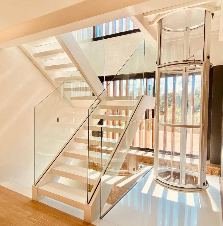 Two-story house with white staircase and glass railing.