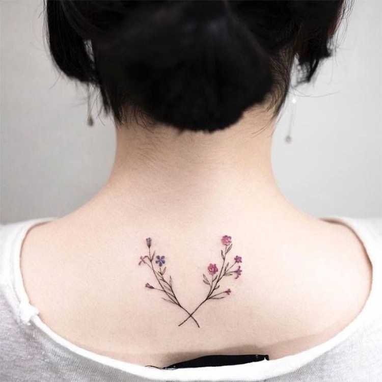 Female tattoo with flower design on the upper central part of the back near the neck and back of the head