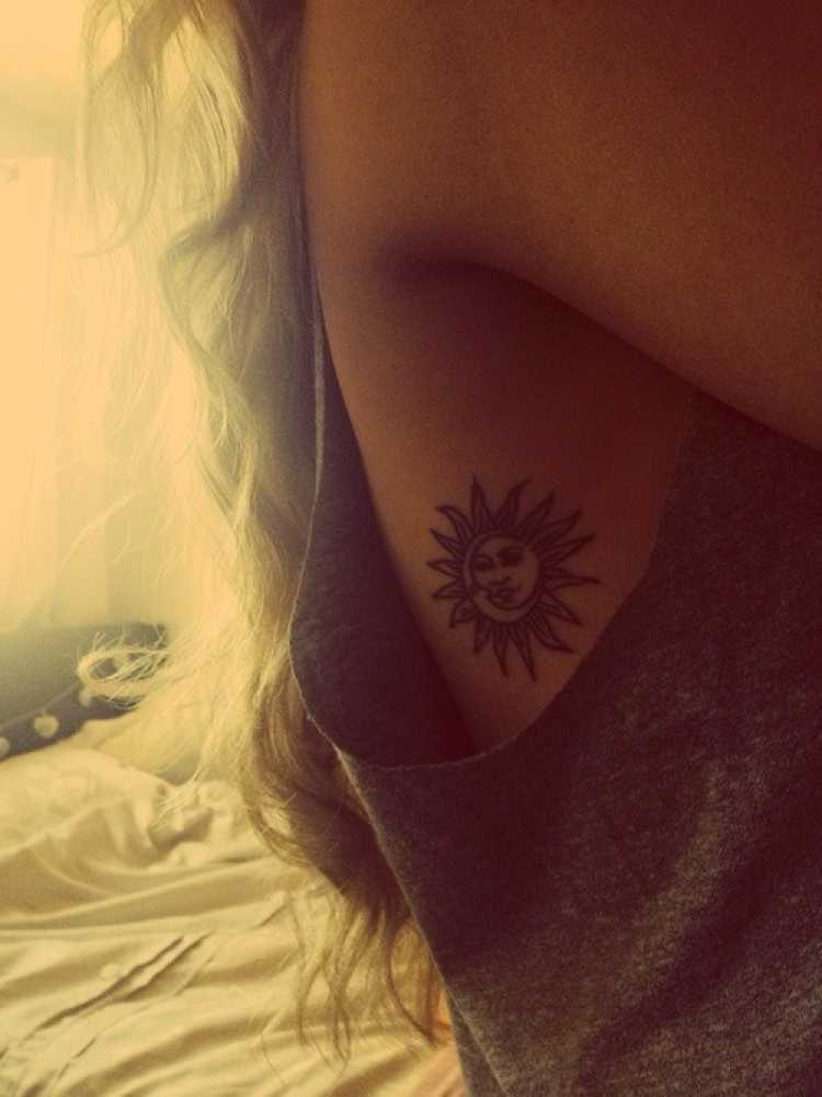 Woman with a sun tattoo on her rib under her arm