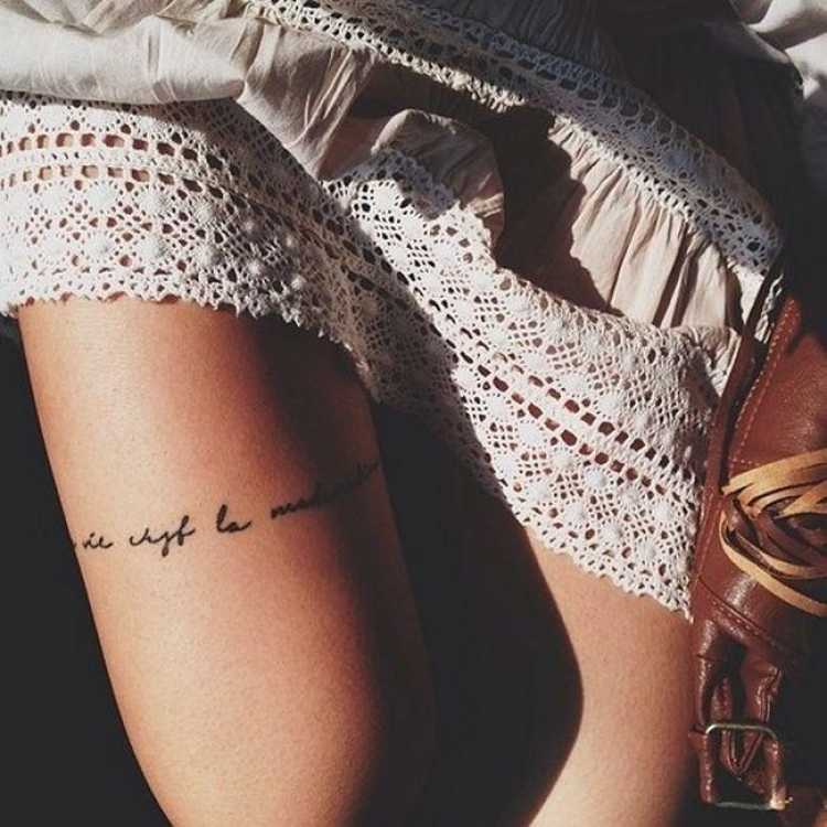 delicate feminine tattoo with words on the thigh