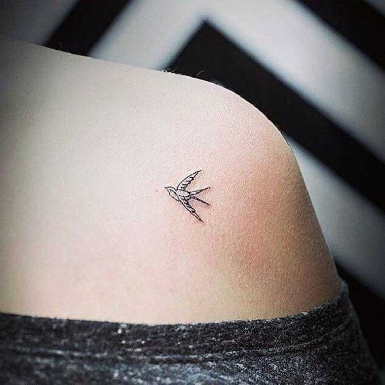 Delicate feminine tattoo with a bird on the shoulder