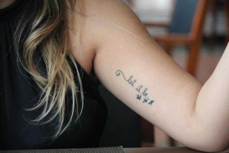 Delicate feminine tattoo with words on the side of the arm