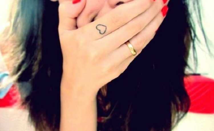 Female tattoo on the finger in the shape of a heart