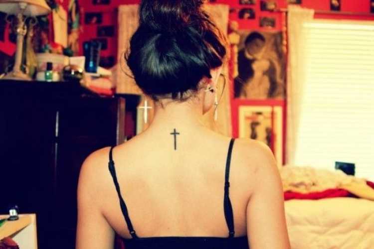 Female tattoo in the shape of a crucifix on the back of the neck