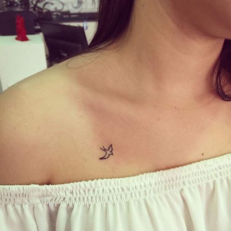 Delicate flying bird tattoo on lap next to shoulder