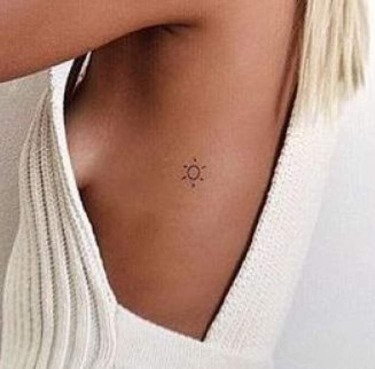 Delicate sun tattoo on rib