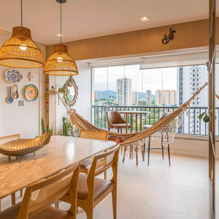 Dining room with granite table integrated with balcony, where there is a hammock, a high table and two brown leather stools