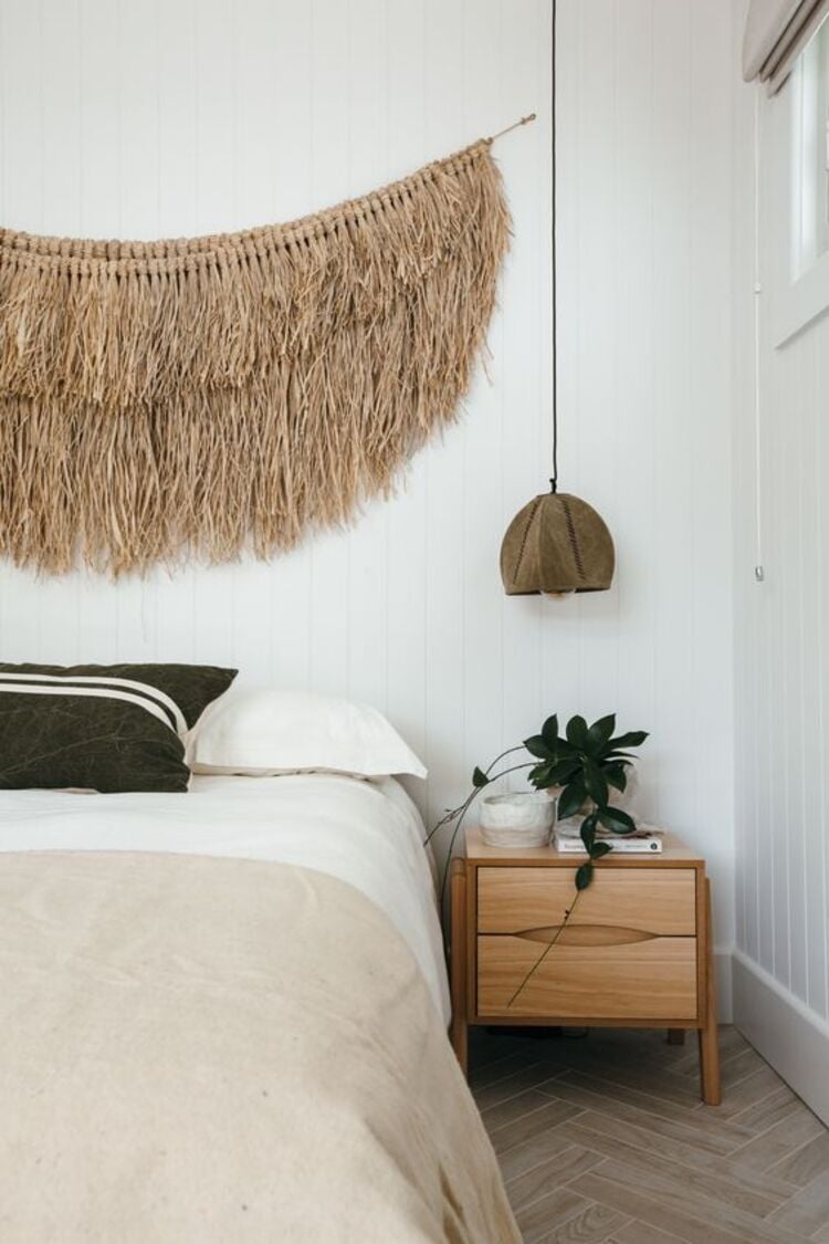 White room with macramé on the wall.