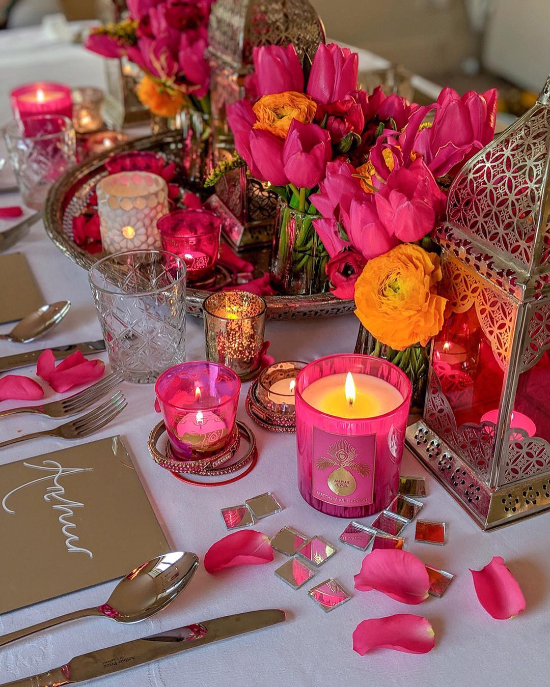 Photo of table decorated with roses, petals and candles in shades of pink