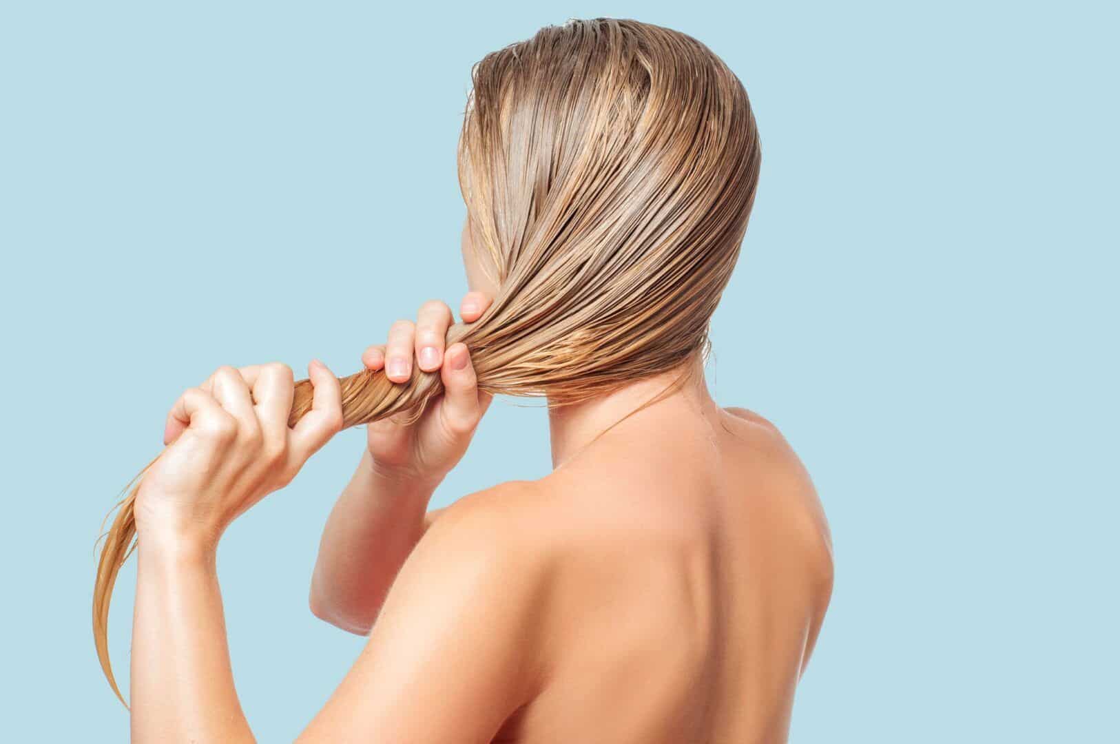 Blonde woman moisturizing her hair.