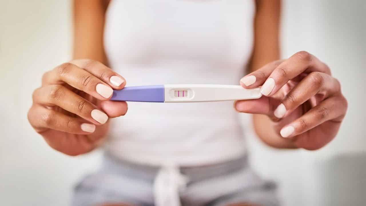 Woman shows positive pregnancy test.