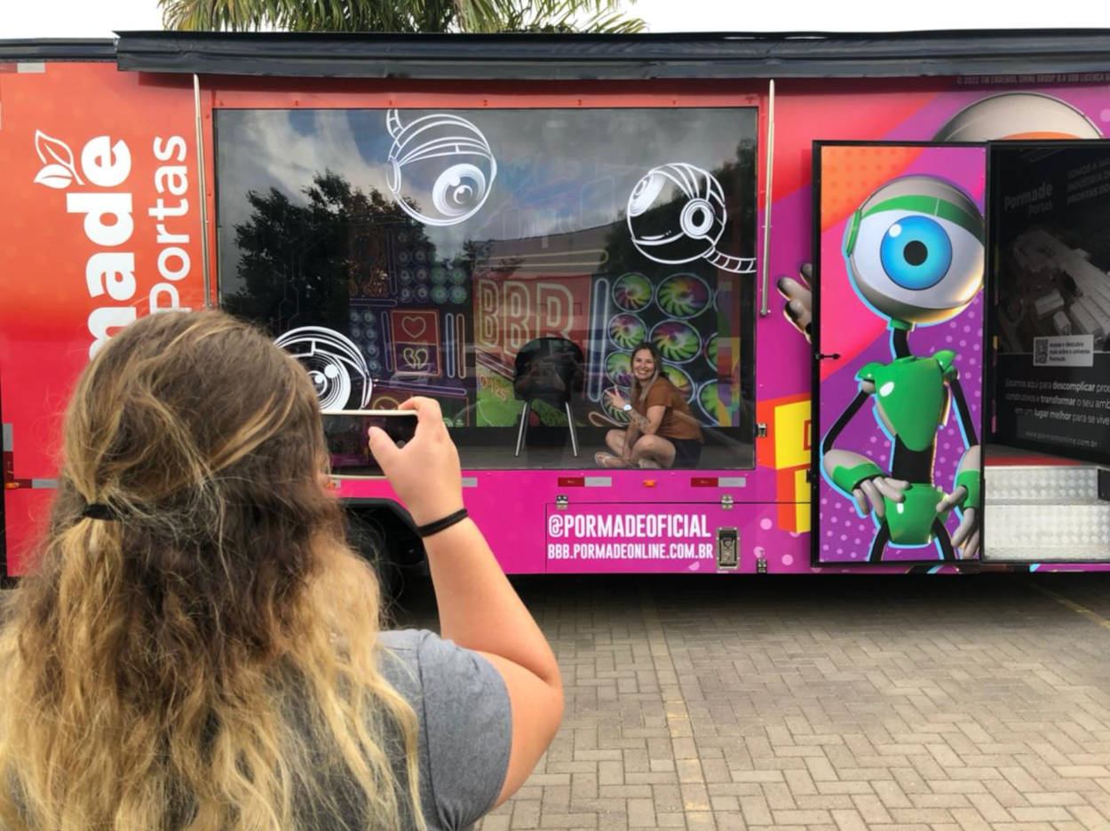 Woman taking a photo of her friend in the BBB 22 themed truck.