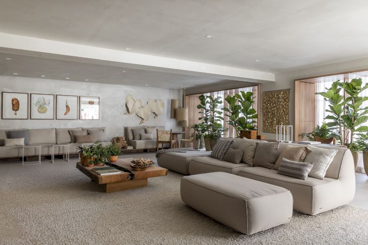 Living room decoration that contributes to mental health, with neutral colors, beige sofas and armchairs, decorative plants, leaf decorative items and paintings in earthy tones