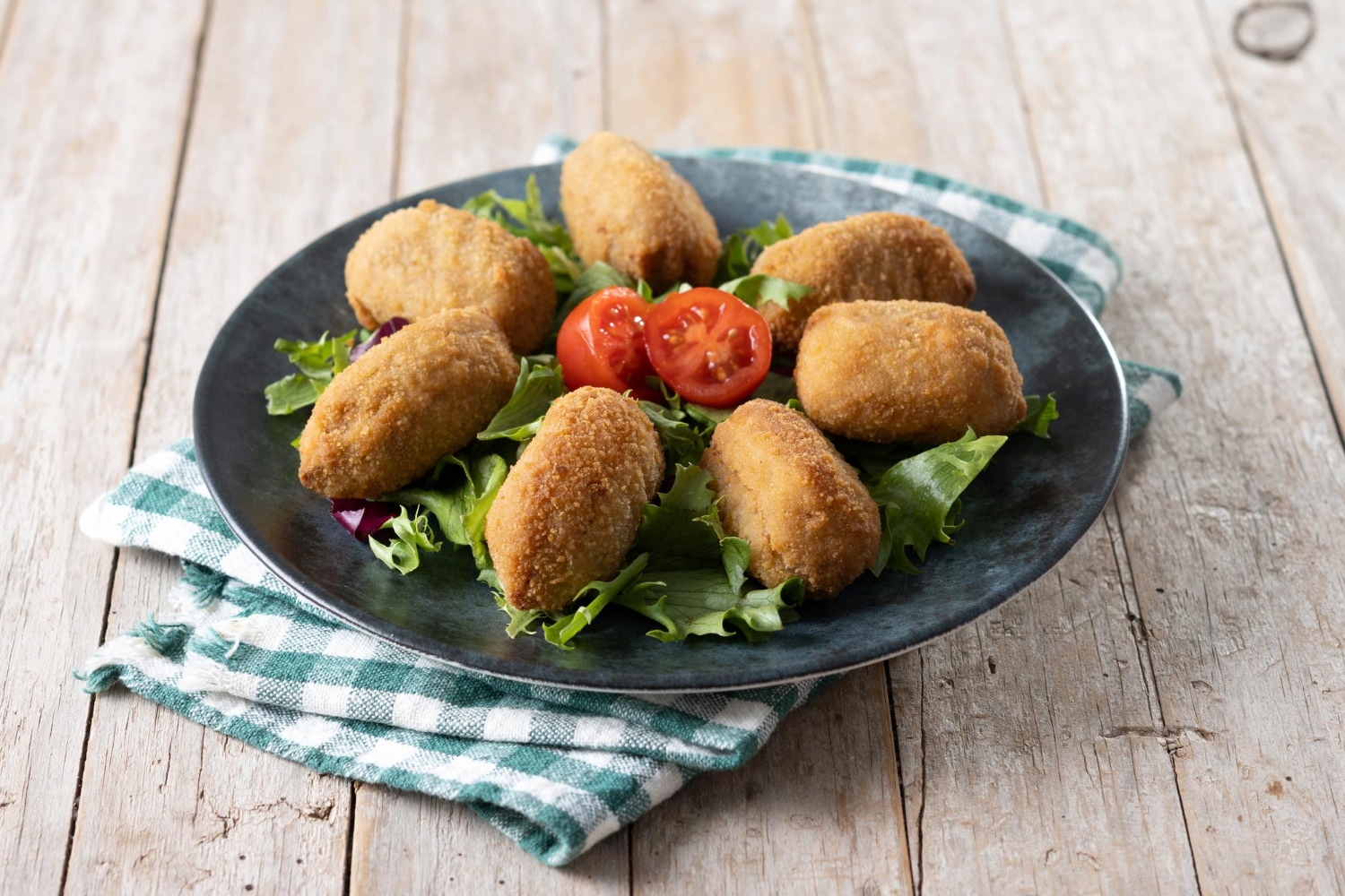 Prato servindo bolinho de bacalhau com salada como opção para o almoço de Páscoa