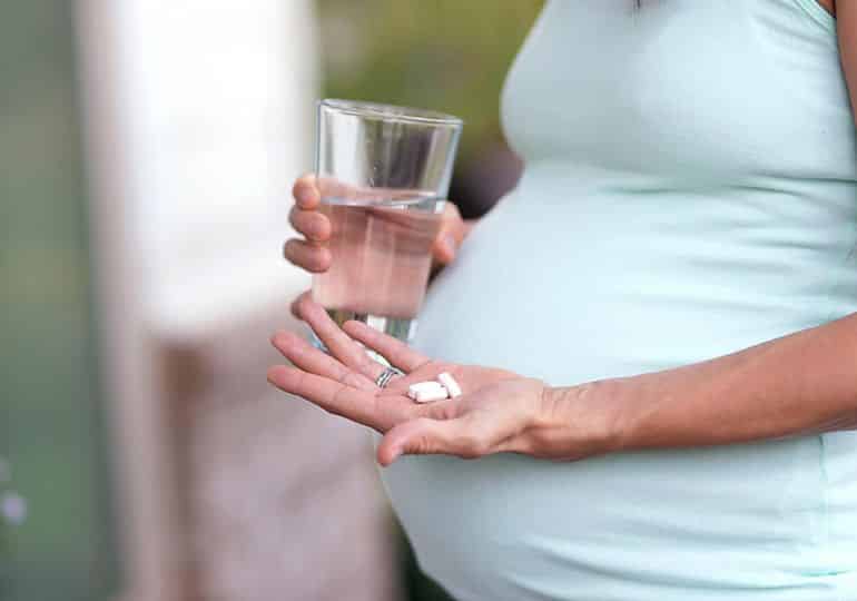 pregnant woman with medicine in hand