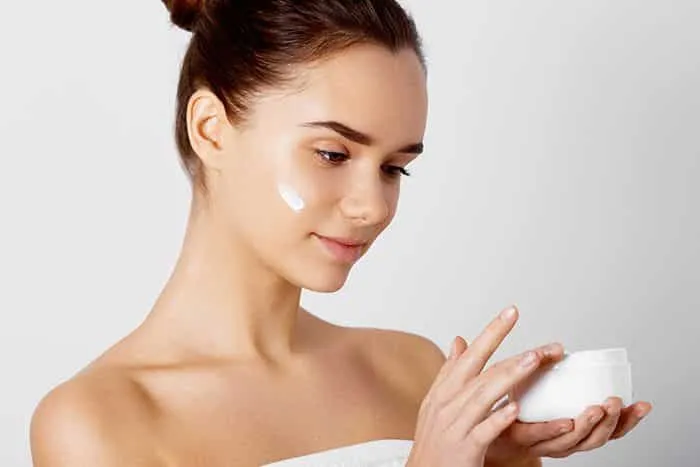 woman moisturizing her skin at home