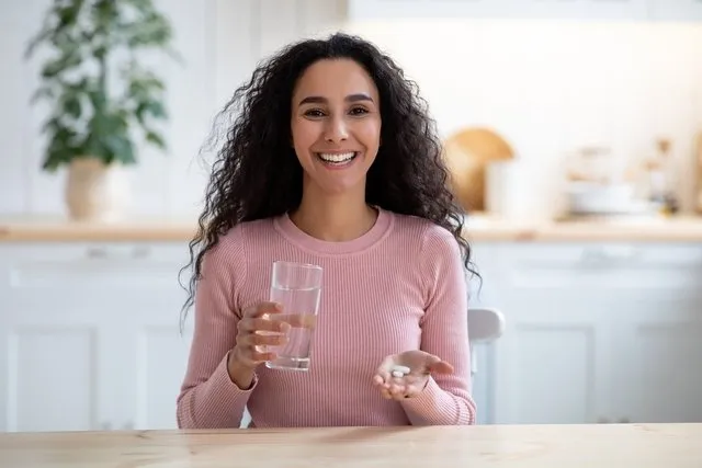 A woman with a glass of water and a pill to take