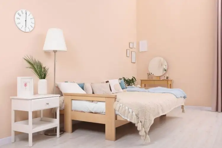 Room light pink, with a bed full of pillows and mobile in white, and a lamp