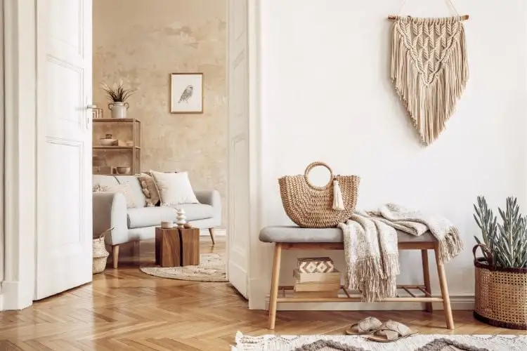 Entrance Hall and part of the living room in a boho style with a macramê na parede, a lot of the wood, the sofa's low, plants, and knitting.