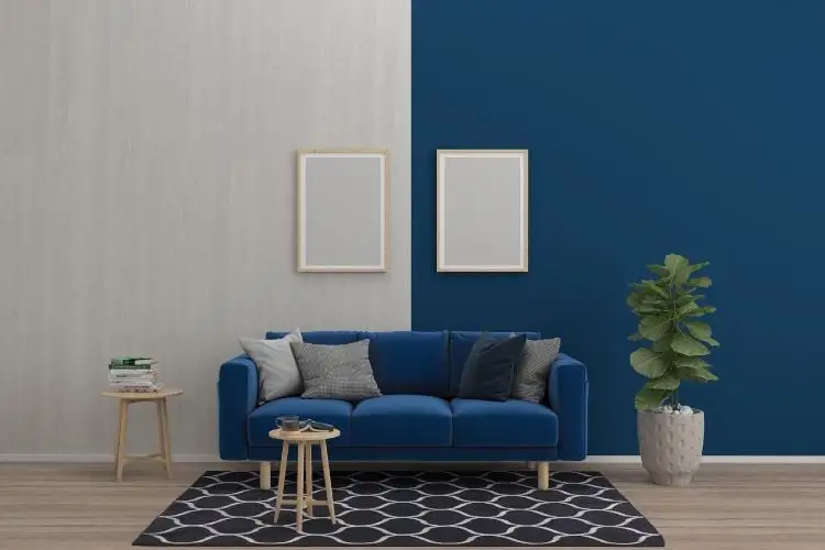 A living room with a wall of half-blue and half-light wood, with a blue sofa, throw pillows, white, and gray, plant, and rug in geometric shape