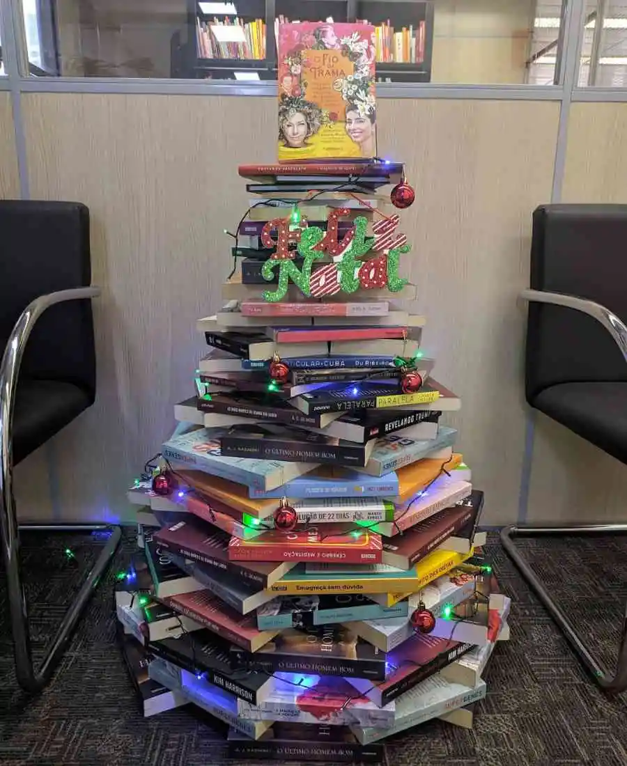 Foto de árvore de Natal feita de livros com decorações natalinas.