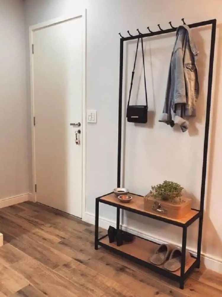 Chaussure rack banc avec un ara, sacs à main, et les manteaux suspendus dans. Ce meuble a été placée dans le hall d'entrée d'une maison avec une porte en bois sur un mur blanc et de gris, bien sûr. 