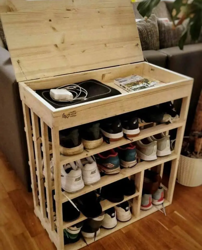 Chaussure rack faite de palettes en bois, rustique. Au sommet il y a un espace pour stocker des petits objets, comme un livre ou un magazine. 